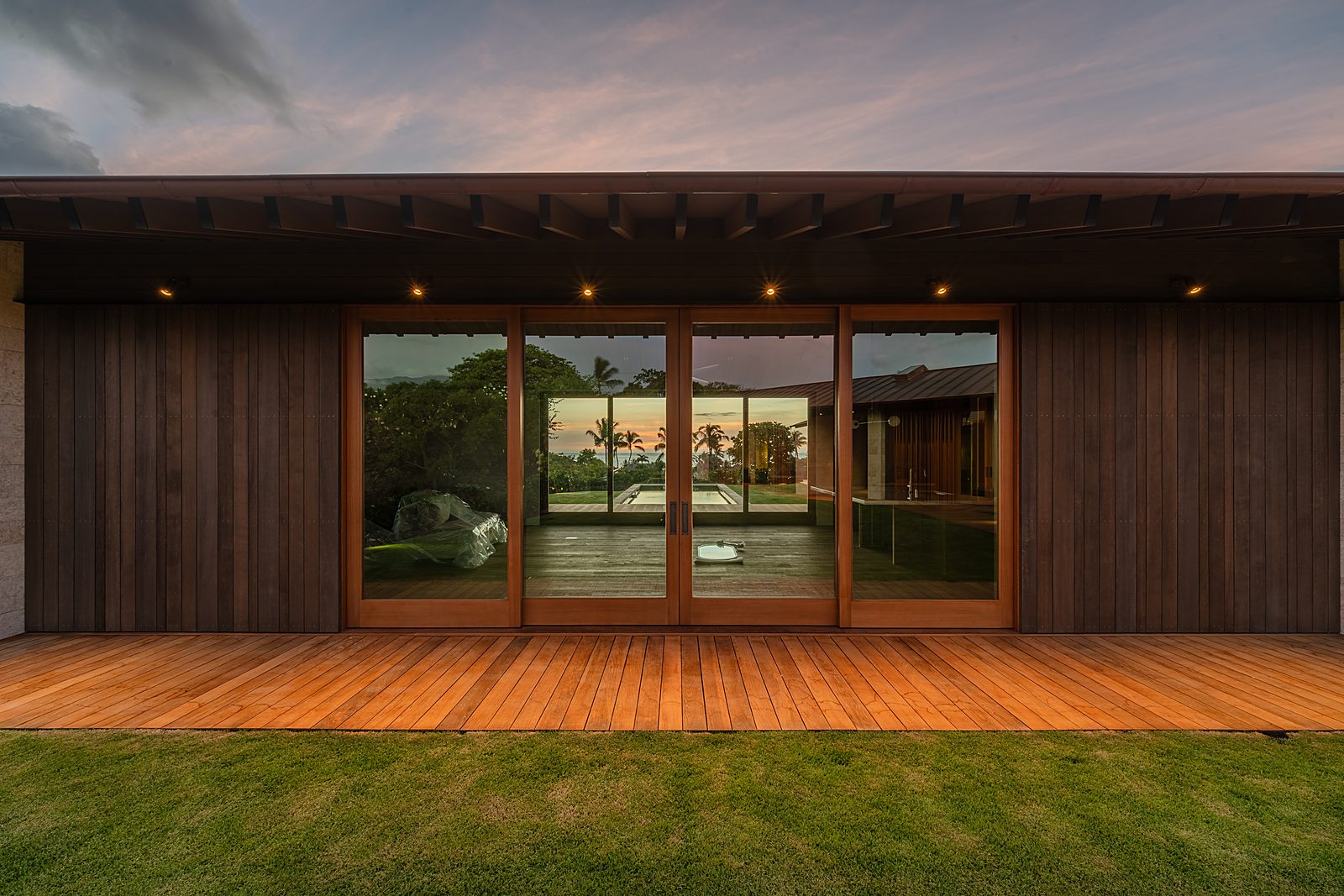 Cedar-clad residence at dusk, sunset reflected in the glass doors