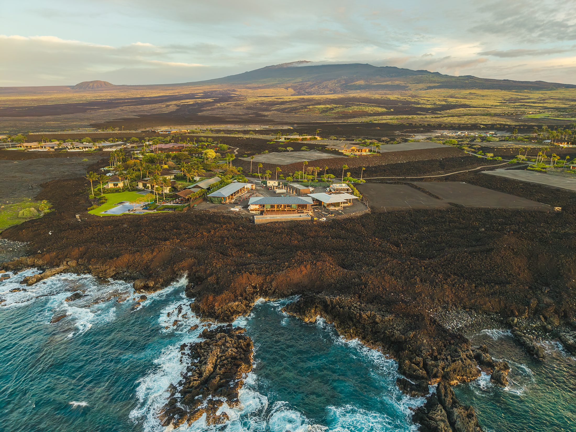 Aerial of the lava coastline and turquoise surf at last light